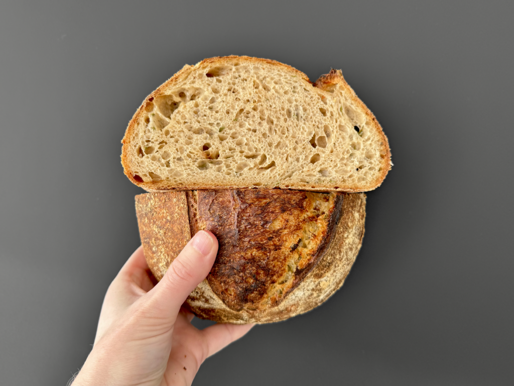 Dit wit desembrood wordt extra bijzonder door de toevoeging van gepofte knoflook en verse rozemarijn, die samen zorgen voor een rijke, aromatische smaak. De knoflook wordt langzaam geroosterd tot een zachte, zoetige pasta en verwerkt in het deeg tijdens de derde stretch & fold. Dankzij de Aliquot-methode houd je de fermentatie perfect onder controle, wat resulteert in een luchtig en smaakvol brood met een knapperige korst.