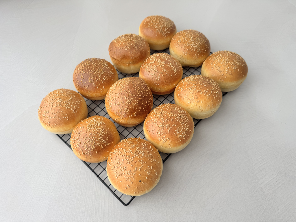 Deze zachte en luchtige zuurdesem brioche hamburgerbroodjes hebben een rijke, boterige smaak en een subtiele zuurdesemtoon. Het deeg wordt zorgvuldig gekneed, langzaam gefermenteerd en koel gerezen voor optimale textuur en smaak. Na het vormen rijzen de broodjes verder tot ze luchtig en veerkrachtig zijn. Een glanzende eiwas en een korte baktijd zorgen voor een goudbruine, malse afwerking.